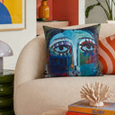 Teal abstract face velvet cushion styled on a sofa