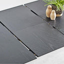A dark charcoal gray wood-look rectangular table with three long panels folded out, shown in a clean studio-style setting with small decorative objects on top.