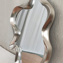 Silver abstract mirror styled on a wall