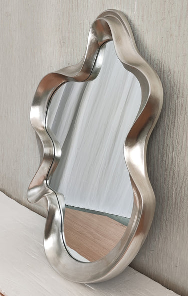 Silver abstract mirror styled on a wall