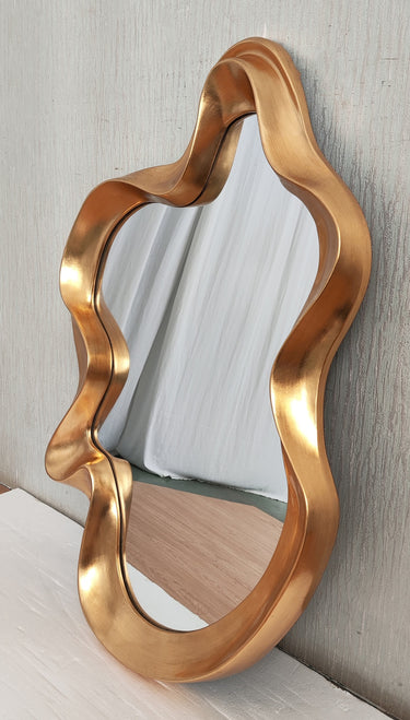 Gold abstract mirror styled on a wall