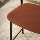 Close-up of the Olly dining chair's burnt orange upholstered seat