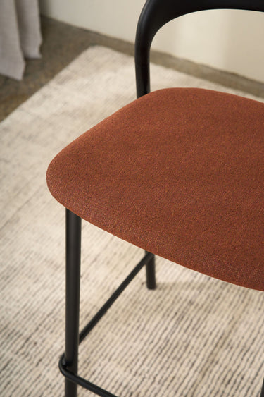 Close-up of the Olly dining chair's burnt orange upholstered seat