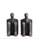 Sitting Man Bookends, a pair of seated-figure sculptures cast in solid cement with a matte charcoal finish