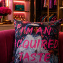 Acquired Taste slogan velvet cushion styled on a sofa
