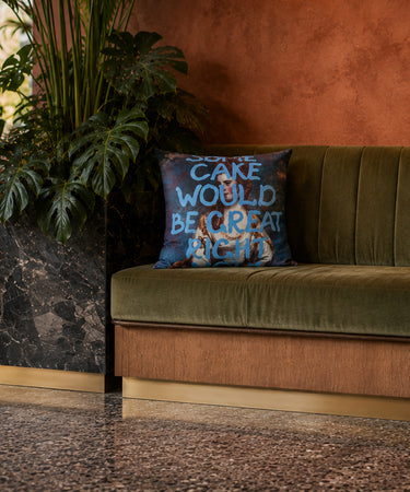 Some Cake slogan velvet cushion styled on a sofa