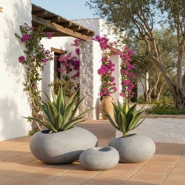 Three round, stone-like decorative planters in light gray, with one planter holding a green succulent, shown on a plain white background.