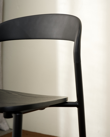 Close-up of the Olly dining chair's curved black backrest